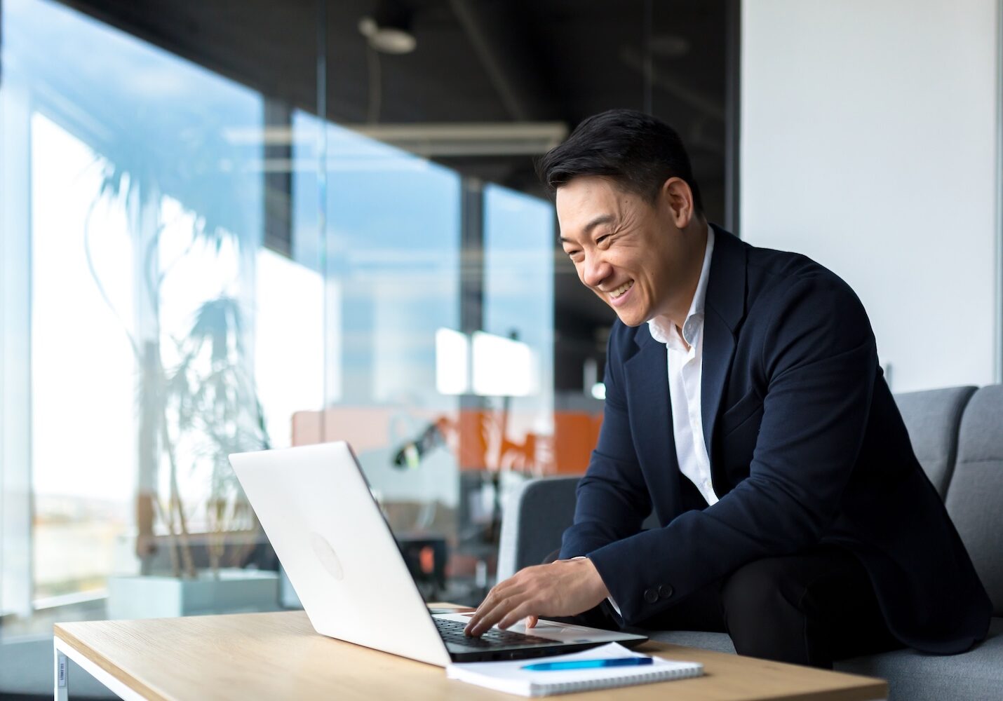 Senior Asian business man working on laptop online, smiling and rejoicing, happy boss business owner working in office